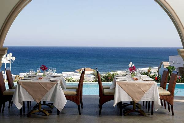Außenrestaurant mit Blick auf das Meer und weißen Gebäuden im Hintergrund.