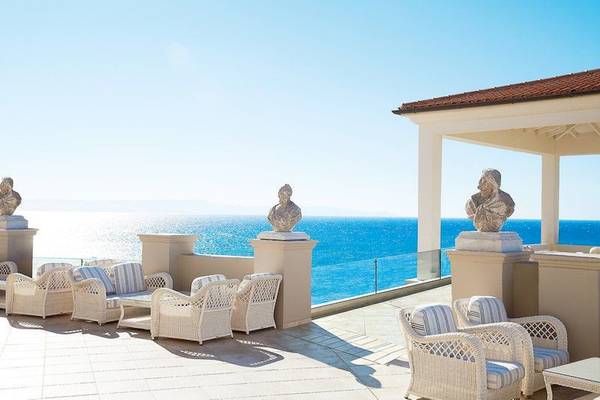 Hotelterrasse mit Blick auf das Meer, Skulpturen und weißen Möbeln.