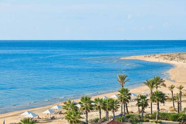 Strand und Hotel in Griechenland mit blauem Meer und weißen Sonnenschirmen