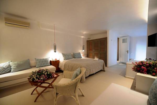 Schlafzimmer im MykonosView Hotel mit einem großen Bett, Sofas, einem Tisch mit Blumen und einer Klimaanlage.