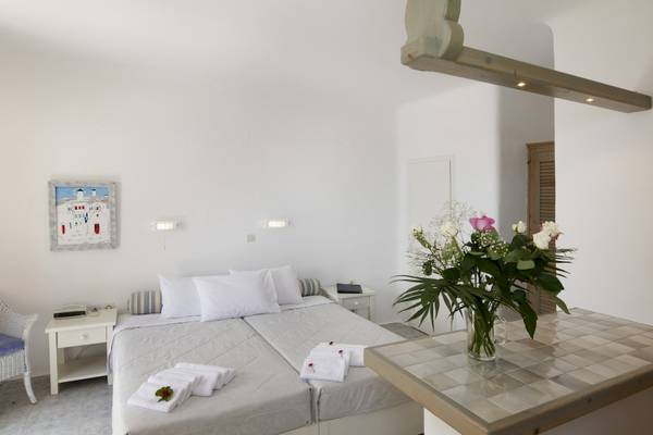 Schlafzimmer im MykonosView Hotel mit zwei Betten, weißen Kissen und einem Blumenstrauß in einer Vase.