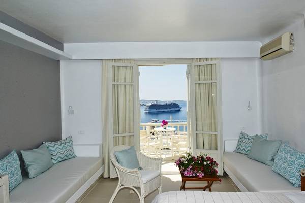 MykonosView Hotel Balkon mit Meerblick, Kreuzfahrtschiff und Tisch mit Blumen.
