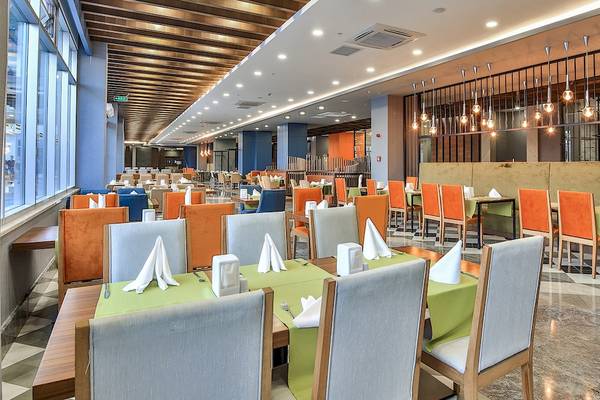 Innenansicht des Restaurants im Saturn Palace Resort mit farbenfrohen Stühlen und Tischen.