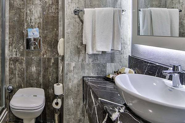 Badezimmer im Saturn Palace Resort mit Dusche, Toilette, Waschbecken und Handtüchern.