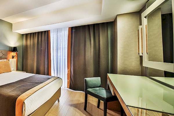 Ein modernes Hotelzimmer im Saturn Palace Resort mit einem großen Bett, Nachttischen, einem Schreibtisch und einem Stuhl.