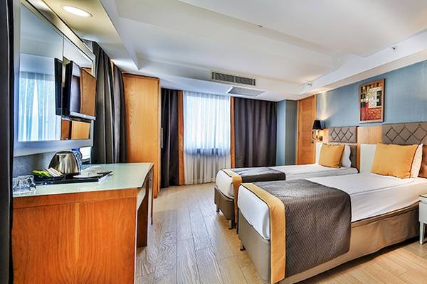 Doppelzimmer im Saturn Palace Resort mit zwei Betten, einem Nachttisch, einem Schreibtisch und einer modernen Einrichtung.