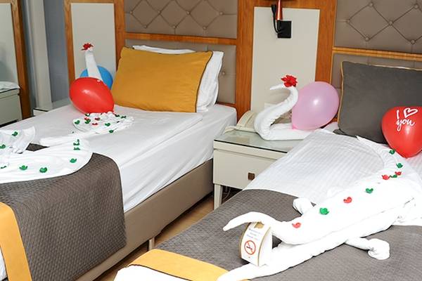 Zwei Betten im Saturn Palace Resort mit roten Ballons und Liebesbotschaften.
