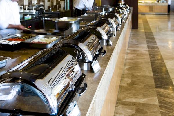 Buffet-Tisch im Saturn Palace Resort mit verschiedenen Speisen und Kellnern im Hintergrund.
