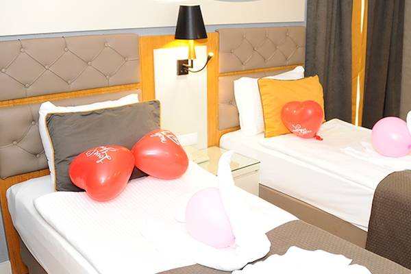 Zwei Zimmer im Saturn Palace Resort mit roten Herz-Ballons und weißen Handtüchern.