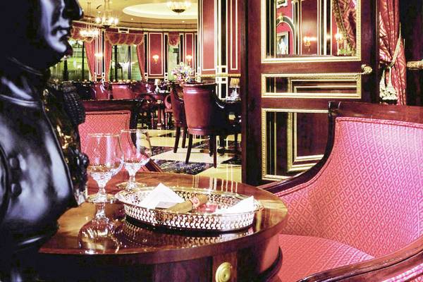 Innenbereich des Paris Las Vegas Hotels mit rotem Dekor, Stühlen, Tisch, Statue und Gläsern.