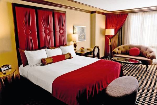 Ein elegantes Hotelzimmer im Paris Las Vegas mit einem großen Bett, rotem Dekor und Möbeln.