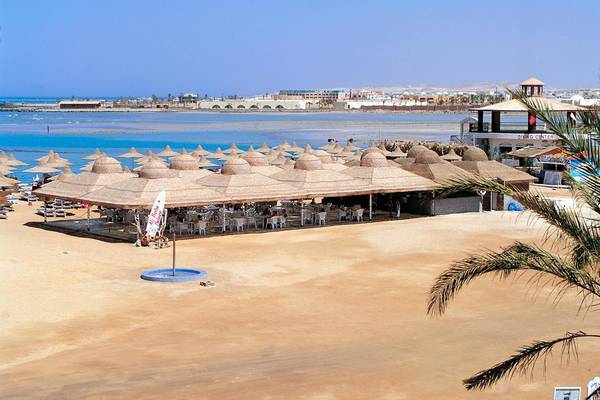 Luftaufnahme des Ali Baba Palace Strandes mit vielen Sonnenhuten und einem Tauchzentrum im Hintergrund.