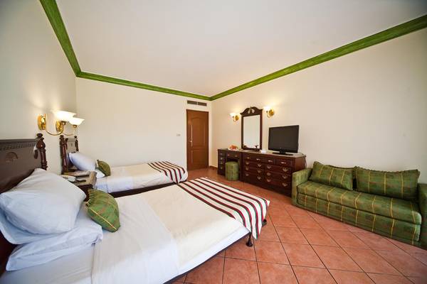 Doppelzimmer im Ali Baba Palast mit zwei Betten, Fernseher und grüner Couch.