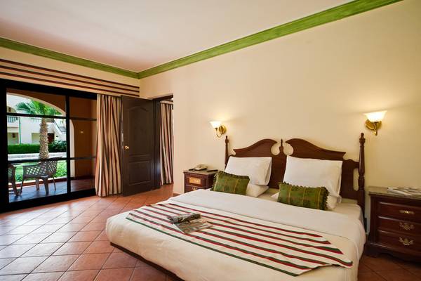 Schlafzimmer im Ali Baba Palace Hotel mit einem Bett, Kissen, Lampen und einer offenen Terrasse.