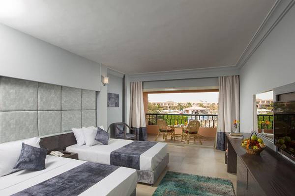 Doppelzimmer im Ali Baba Palace mit zwei Betten, einem Balkon und einem Tisch mit Früchten.