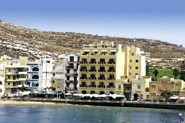 Außenansicht des Saint Patrick's Hotel Gozo mit Blick auf die Bucht und das Meer.