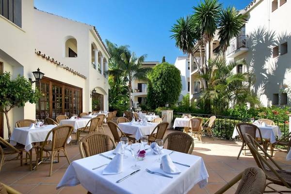 Außenbereich des Bluebay Banus Hotels mit mehreren gedeckten Tischen im Freien.