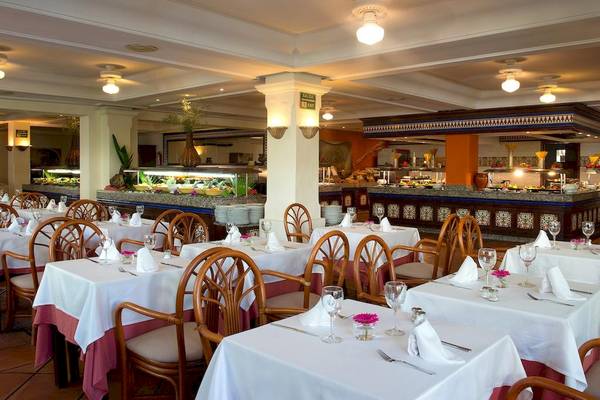 Eines der Restaurants im Bluebay Banus Hotel mit gedeckten Tischen und Buffet im Hintergrund.