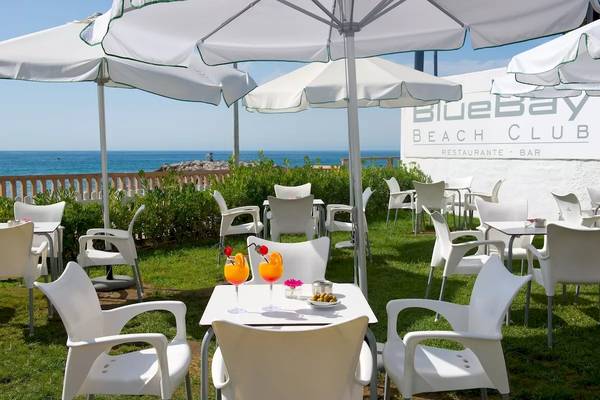 Terrasse im Bluebay Beach Club mit Blick auf das Meer und weiße Möbel