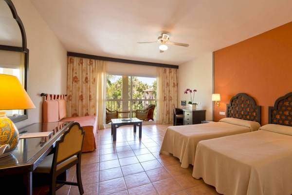 Doppelzimmer im Bluebay Banus Hotel mit zwei Betten, Schreibtisch, Lampe und Balkon.
