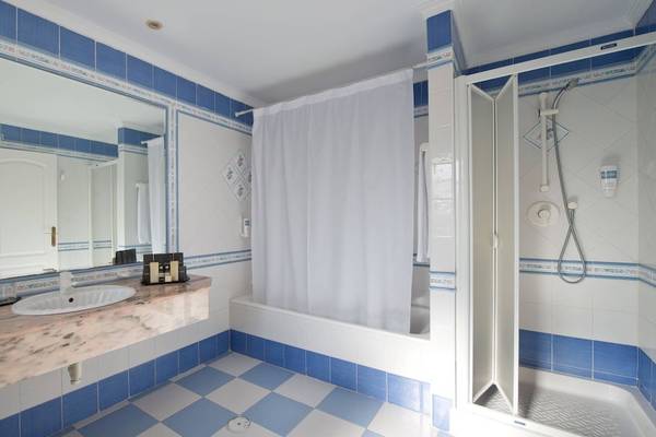 Badezimmer im Bluebay Banus Hotel mit blauen Fliesen und Marmorarbeitsplatte.