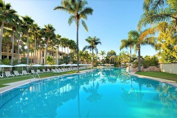 Außenpool des Bluebay Banus Hotels mit Liegestühlen und Palmen