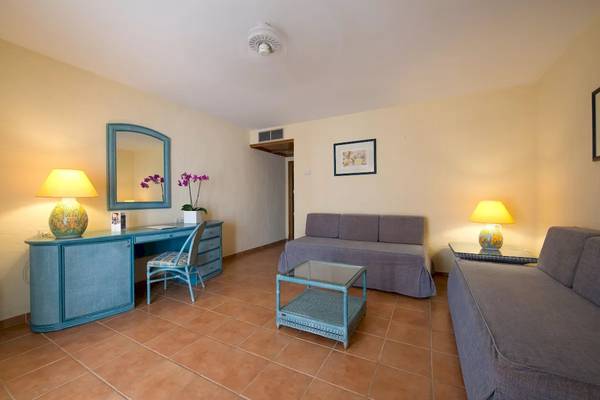 Wohnzimmer im Bluebay Banus Hotel mit Schreibtisch, Stühlen, Sofas und Lampen.
