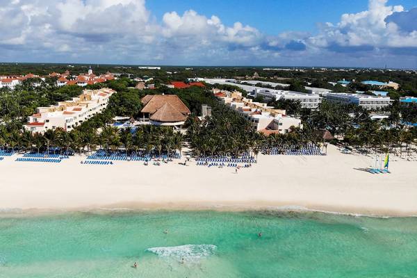 Luftaufnahme des Viva Wyndham Maya Hotels an einem weißen Sandstrand mit blauem Wasser und vielen Liegestühlen.