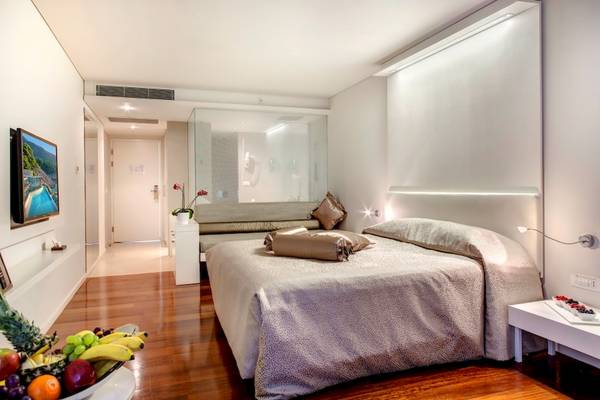 Schlafzimmer im Rixos Premium Dubrovnik Hotel mit Bett, Obstschale und Fernseher.