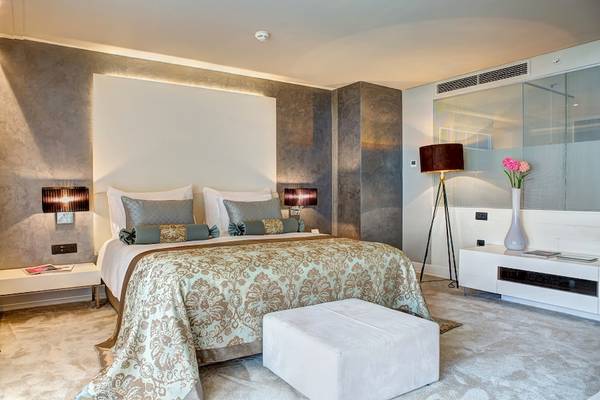 Luxuriöses Schlafzimmer im Rixos Premium Dubrovnik mit gemusterter Bettwäsche und weißen Möbeln.