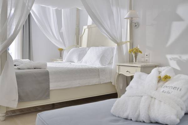 Schlafzimmer im Kamari Hotel mit einem Bett, das unter einem Baldachin versteckt ist.