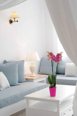 Wohnzimmer des Kamari Hotels mit weißem Sofa, Kissen, Tisch, Lampe und Orchidee