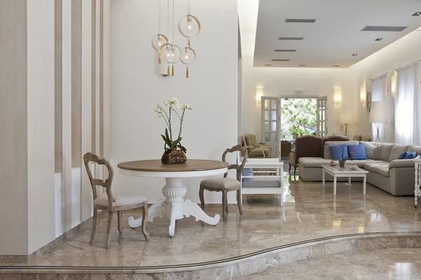 Wohnzimmer des Kamari Hotels mit weißem Tisch, Stühlen, Couch und hellem Interieur