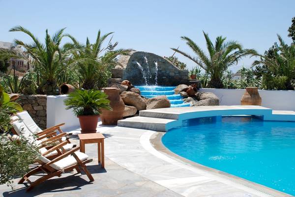 Pool-Terrasse des Kamari Hotels mit Wasserfall und Lounge-Stuhl.