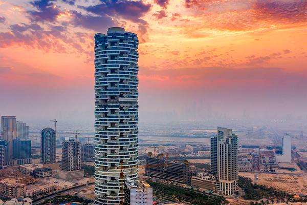 Luftaufnahme des FIVE Jumeirah Village Hotels bei Sonnenuntergang mit mehreren Hochhäusern im Hintergrund.