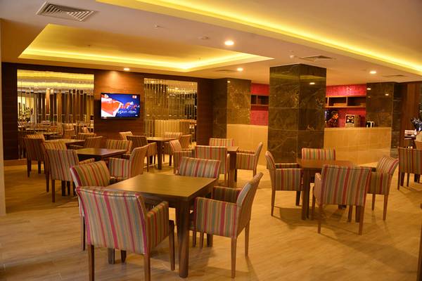 Innenbereich des Sunmelia Beach Resort Hotel & Spa mit Tisch und Stühlen, Fernseher und Bar.