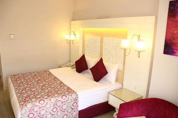 Hotelzimmer im Sunmelia Beach Resort Hotel & Spa mit Doppelbett, zwei Nachttischen und Wandgemälde.