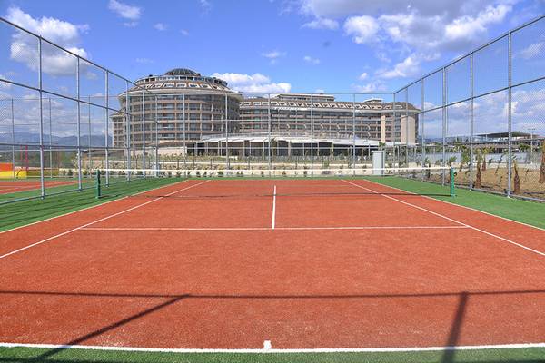 Tennisplatz vor dem Sunmelia Beach Resort Hotel & Spa mit leerem Platz und umzäuntem Bereich.