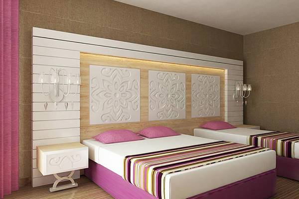 Zwei Betten im Zimmer des Sunmelia Beach Resort Hotel & Spa mit weißen und pinkfarbenen Kopfteilen und gemusterten Bettdecken.