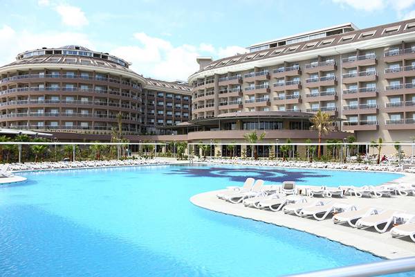 Hotelanlage mit Schwimmbad und Liegen vor einem großen Gebäudekomplex