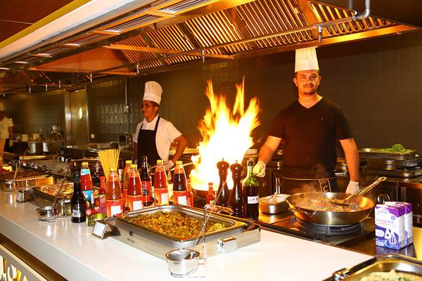 Zwei Köche im Sunmelia Beach Resort Hotel & Spa stehen in der Küche vor einer Flamme und bereiten Essen zu.