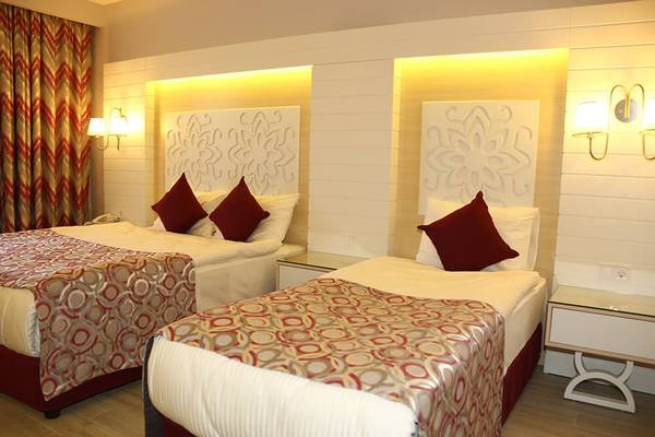 Zimmer im Sunmelia Beach Resort Hotel & Spa mit zwei Betten, dekorativen Kissen und Nachttischen.