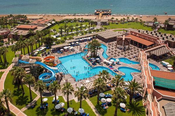 Luftaufnahme des Megasaray Club Belek Resorts mit großen Swimmingpools, Wasserrutschen und umliegenden Palmen.