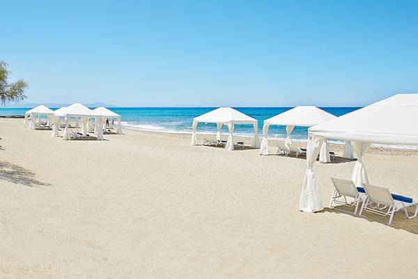 Strand des Grecotel Caramel Boutique Resorts mit weißen Sonnenzelten und Sonnenliegen