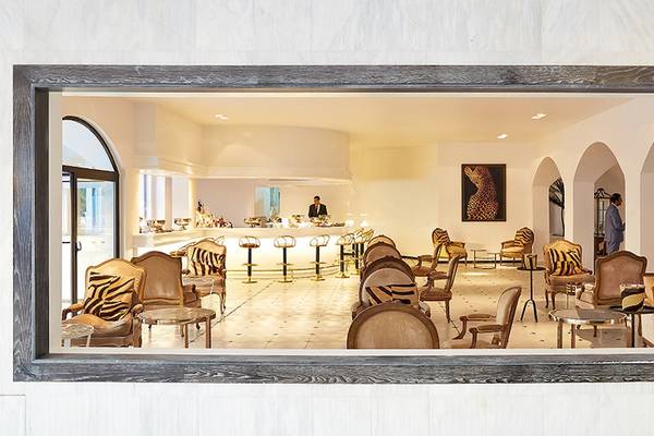 Blick auf die Lounge des Grecotel Caramel Boutique Resort mit Zebramuster-Stühlen und Bar.