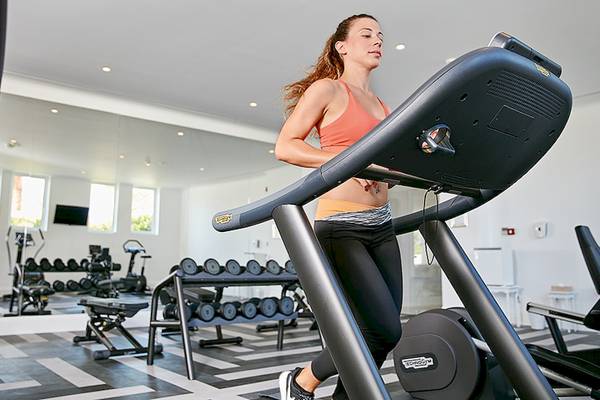 Eine Frau im Fitnessstudio läuft auf einem schwarzen Laufband.