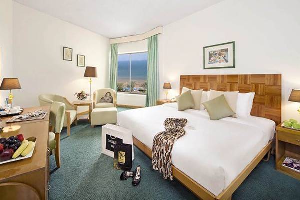 Innenansicht eines Zimmers im BM Beach Hotel mit Bett, Schreibtisch, Fernseher und Fenster mit Meerblick.