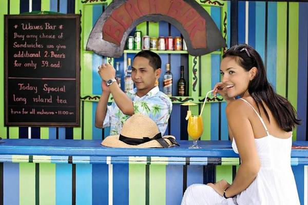 Mann und Frau sitzen an einer Bar im BM Beach Hotel mit Getränken und Blick auf das Menü.