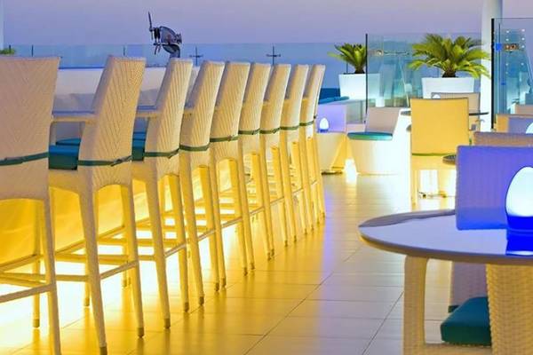 Hotelbar im Hilton Dubai Jumeirah Resort mit gelber Beleuchtung und weißen Stühlen.