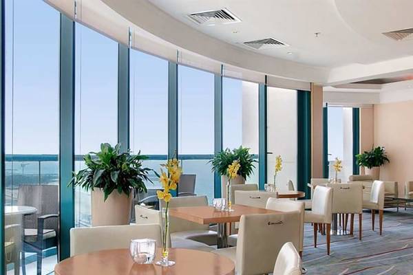 Innenraum des Hilton Dubai Jumeirah Resorts mit mehreren Tischen, Stühlen und großen Fenstern.